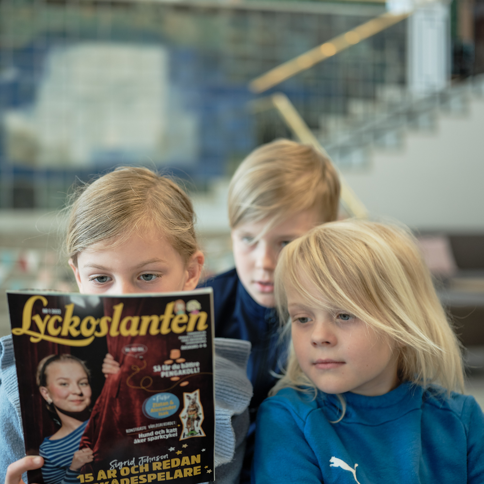 tre barn läser baksidan av en tidning 