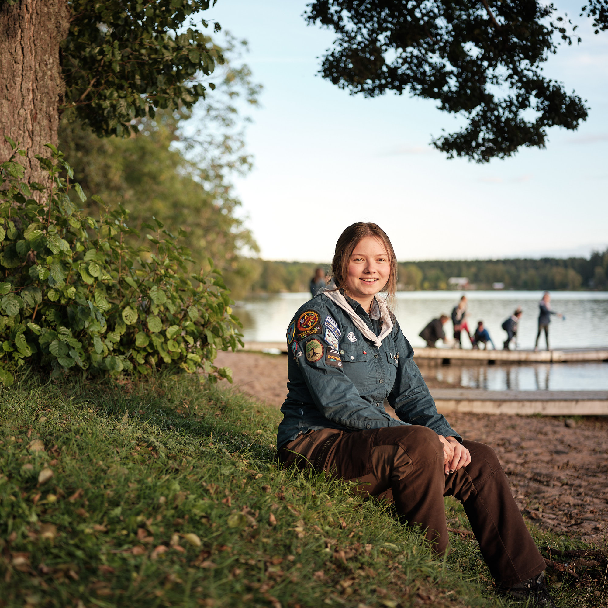En ungdom med scoutskjorta sittandes vid en sjö